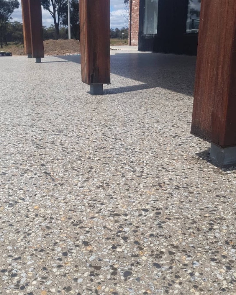 An outdoor alfresco area with an exposed aggregate concrete floor under timber posts