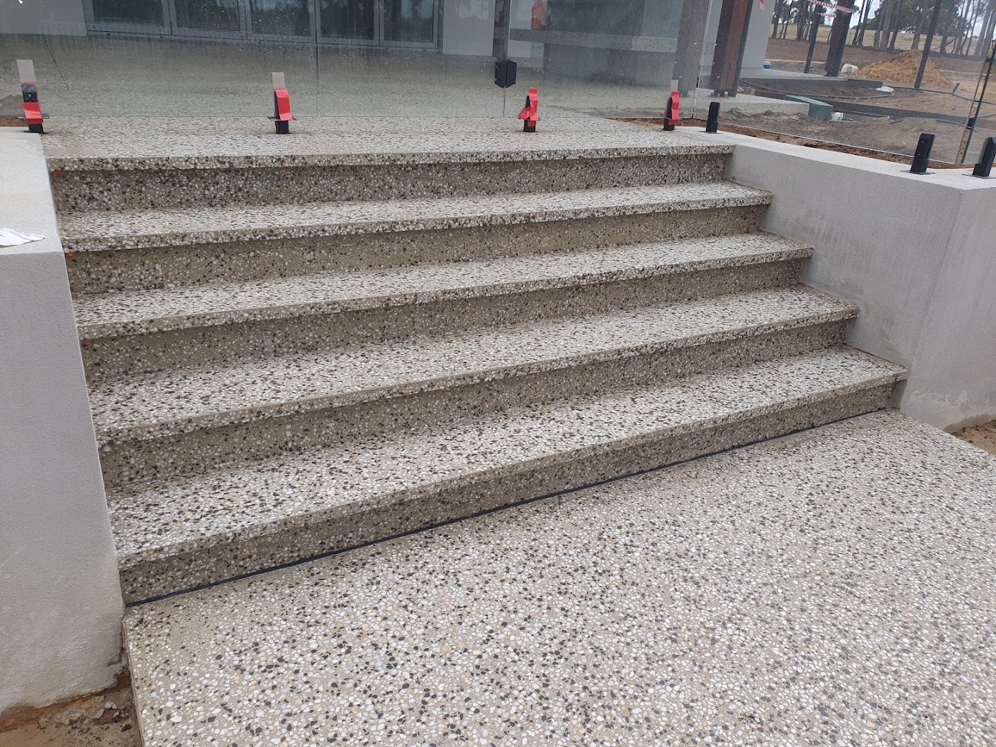 A flight of outdoor concrete steps with an exposed stone finish