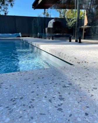 A concrete pool edge with exposed stone through the surface