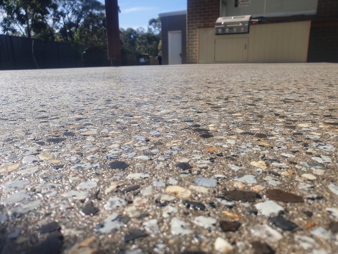 An exposed aggregate outdoor floor beside a barbecue area and a garage