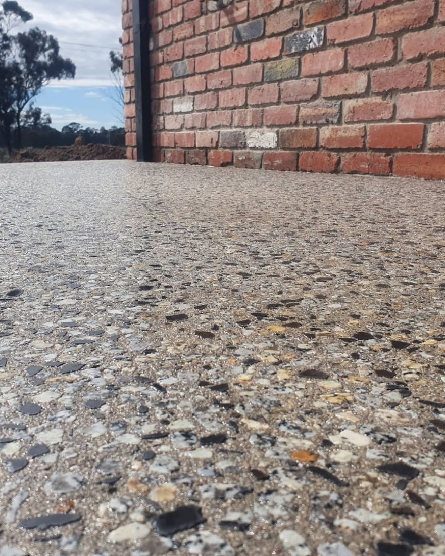 An exposed aggregate floor meeting an old red brick wall