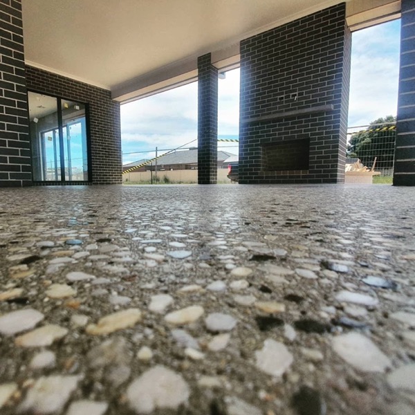 A polished concrete floor reflecting brick pillars and a fireplace