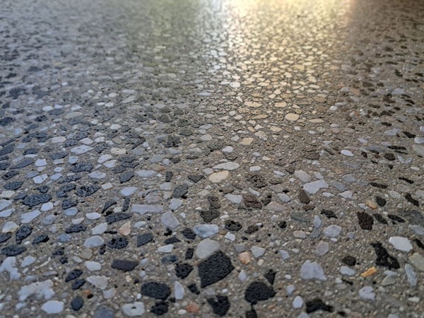 A close view of pale and dark stone across a ground concrete surface