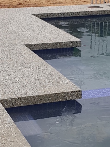 Concrete steps with an exposed stone edge running down into a pool