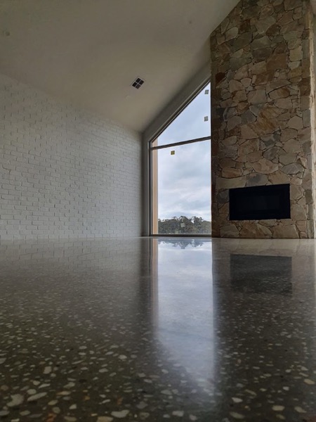A polished concrete floor in a high-ceilinged room with a stone feature wall