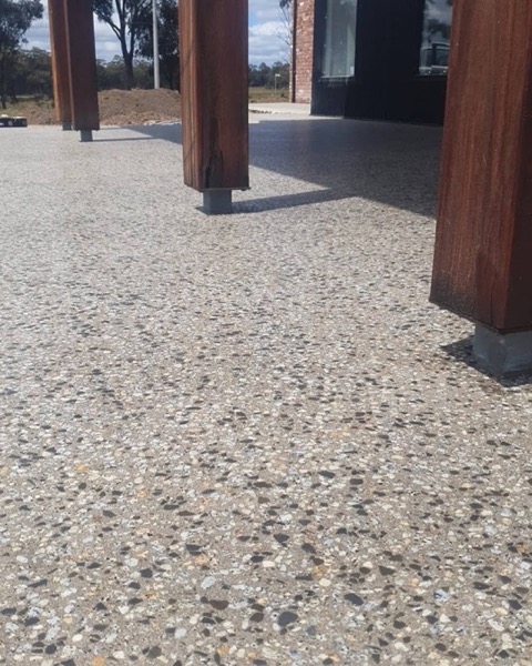 An exposed aggregate concrete floor under timber posts in an alfresco