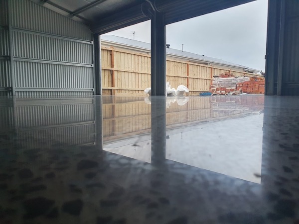 A high-gloss coated concrete floor inside a shed with the door open