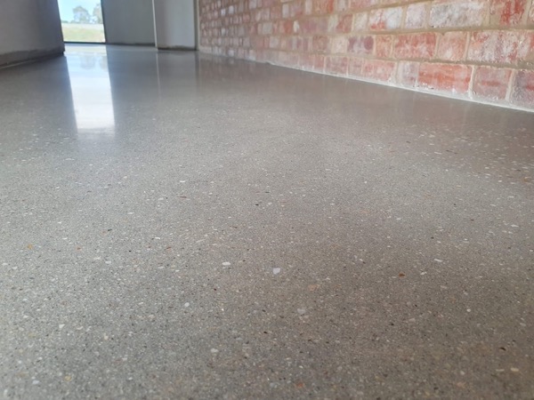 A pale ground concrete floor beside an old brick wall