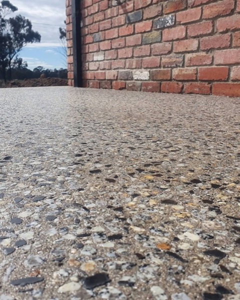 An exposed aggregate concrete floor meeting a red brick wall outside