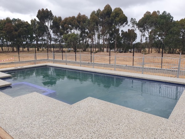 A pool with a concrete surround in an open paddock setting