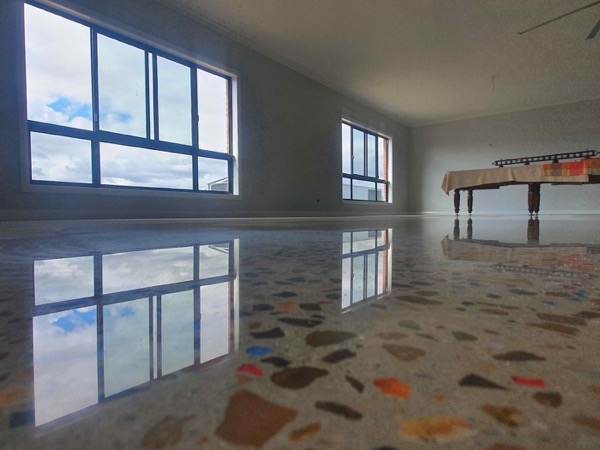 A large room with a polished concrete floor showing coloured stone